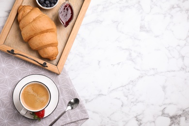 Tasty breakfast with fresh croissant and aromatic coffee on white marble table, flat lay. Space for text