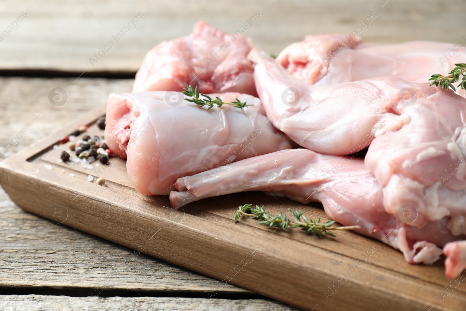 Photo of Fresh raw rabbit meat and spices on wooden table, closeup