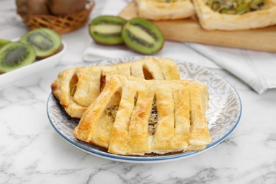 Fresh tasty puff pastry with kiwi on white marble table, closeup