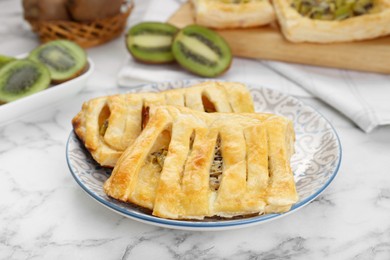 Photo of Fresh tasty puff pastry with kiwi on white marble table, closeup