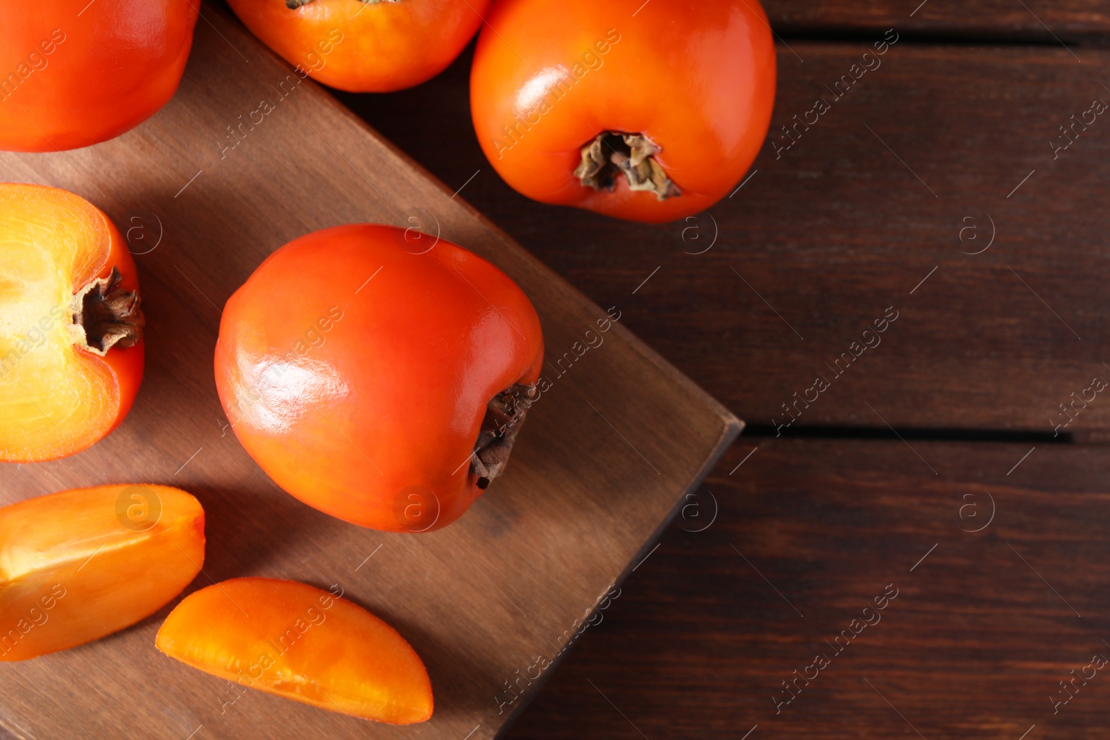 Photo of Delicious ripe persimmons on wooden table, top view. Space for text