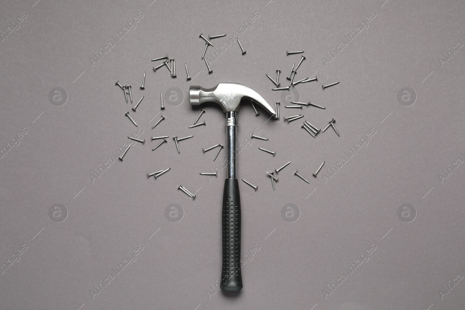 Photo of Hammer and metal nails on grey background, top view