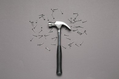 Hammer and metal nails on grey background, top view