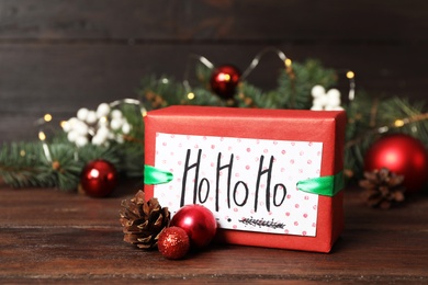 Gift box with Christmas balls and fir tree branches on wooden table