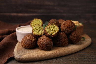 Photo of Delicious falafel balls and sauce on wooden table