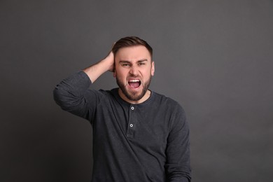 Photo of Portrait of emotional young man on grey background. Personality concept