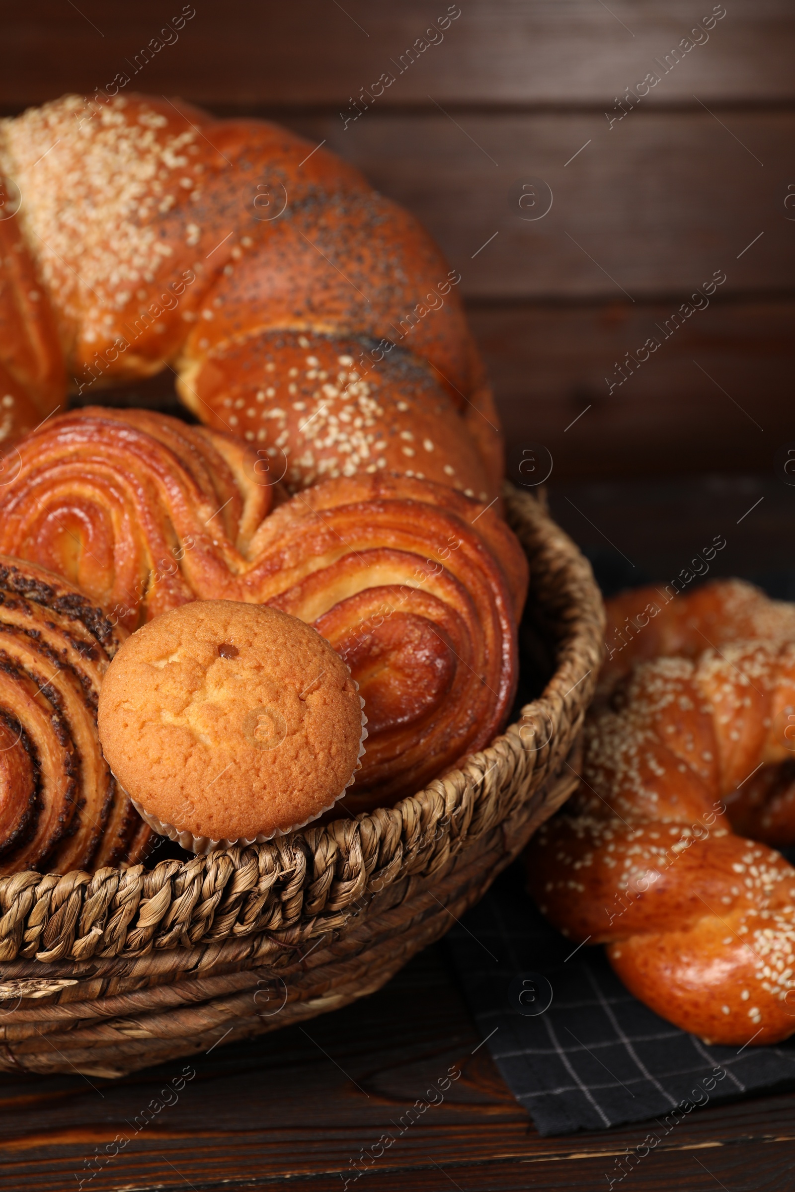 Photo of Wicker basket with different tasty freshly baked pastries on wooden table