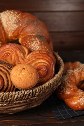Photo of Wicker basket with different tasty freshly baked pastries on wooden table