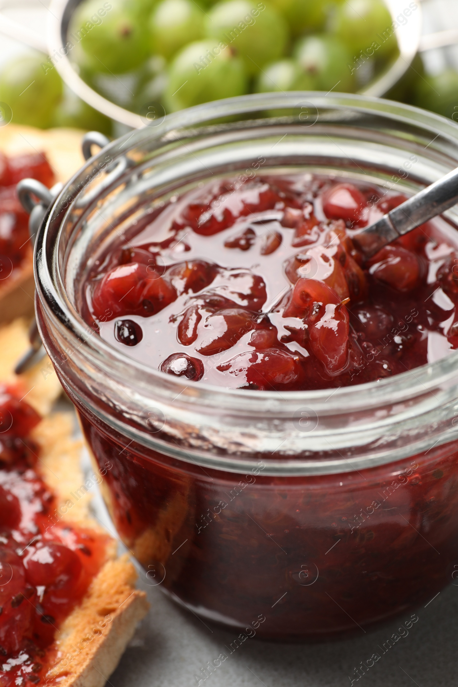 Photo of Jar with delicious gooseberry jam on table, closeup