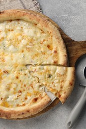 Photo of Delicious cheese pizza and cutter on light grey table, flat lay