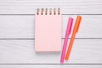 Photo of Notebook and colorful markers on white wooden background, flat lay
