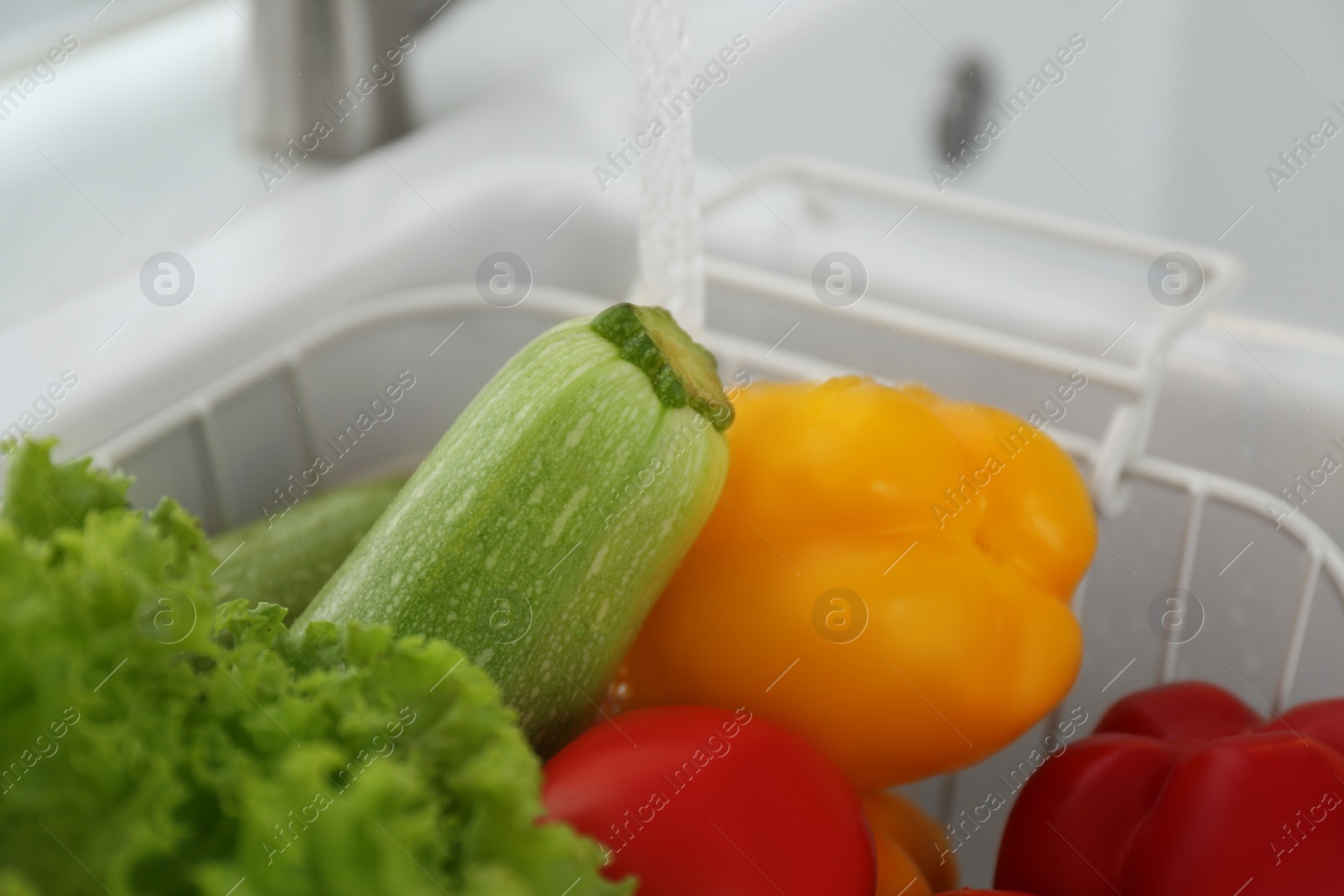 Photo of Many fresh ripe vegetables under tap water in kitchen sink, closeup