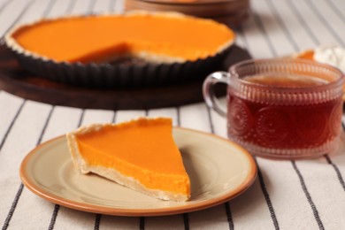 Piece of fresh homemade pumpkin pie served with tea on table