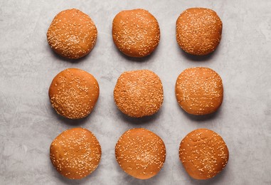 Photo of Fresh buns with sesame seeds on light grey table, flat lay