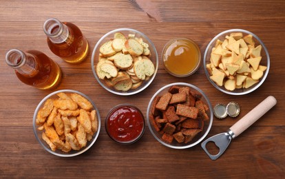 Photo of Different crispy rusks, beer and dip sauces on wooden table, flat lay