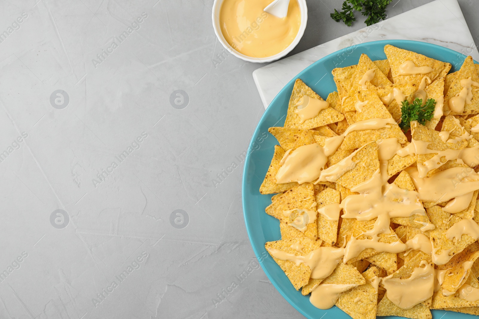 Photo of Plate of Mexican nacho chips with sauce on grey table, flat lay. Space for text