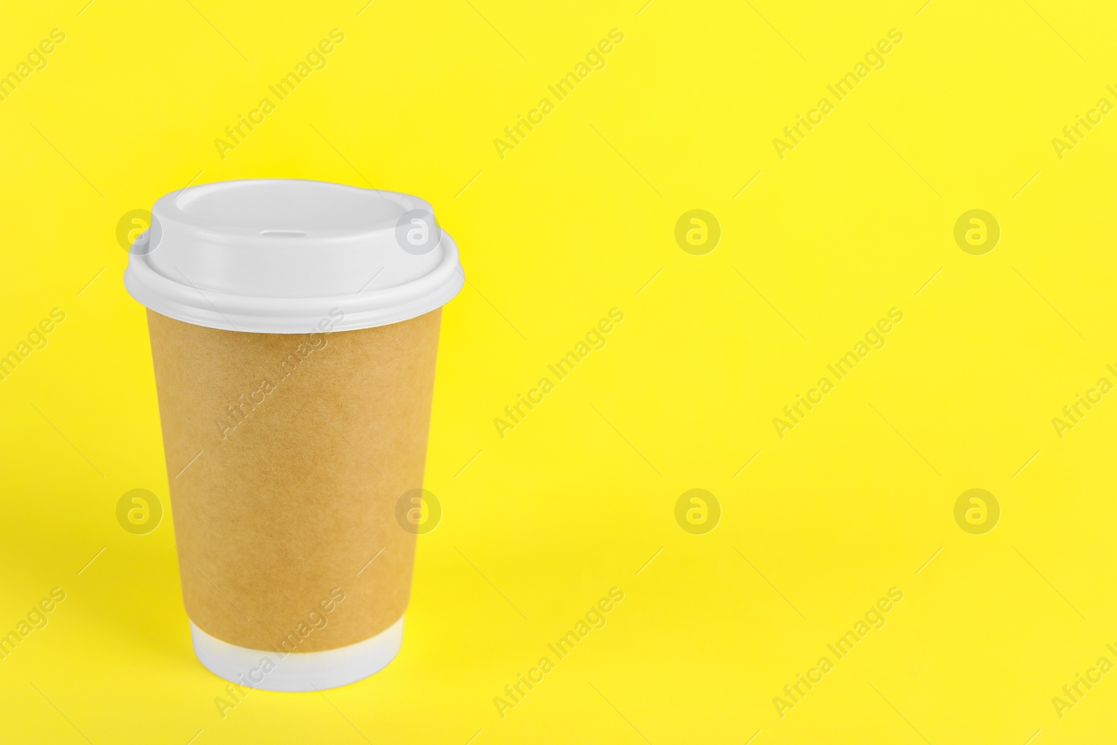 Photo of Paper cup with plastic lid on yellow background, space for text. Coffee to go