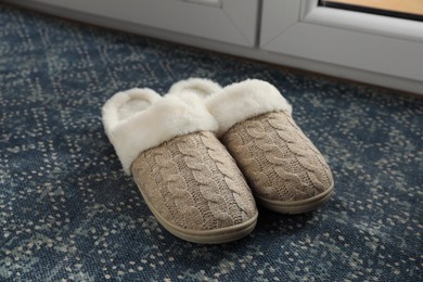 Pair of beautiful soft slippers on mat indoors