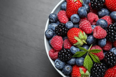 Photo of Mix of ripe berries on grey table, closeup