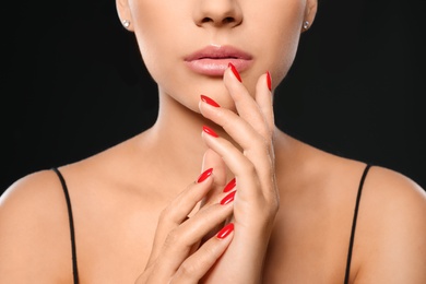 Photo of Beautiful young woman with bright manicure on black background, closeup. Nail polish trends