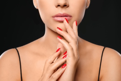 Beautiful young woman with bright manicure on black background, closeup. Nail polish trends