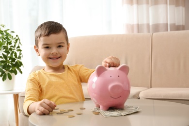 Little boy with piggy bank and money at home