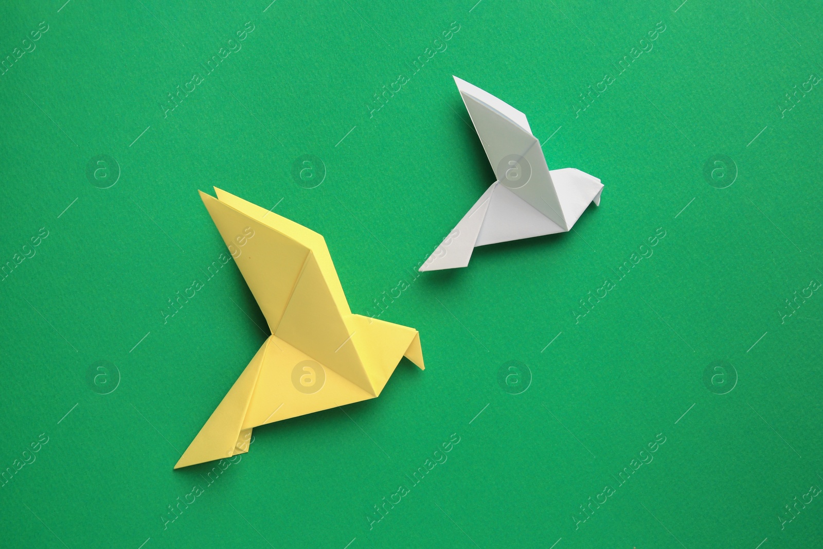 Photo of Beautiful colorful origami birds on green background, flat lay