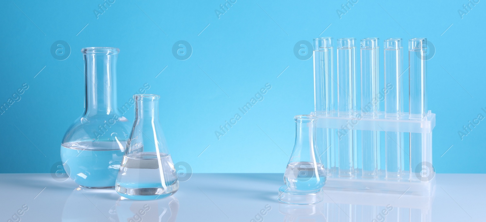 Photo of Laboratory analysis. Glass test tubes and flasks on table against light blue background