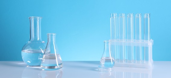 Laboratory analysis. Glass test tubes and flasks on table against light blue background