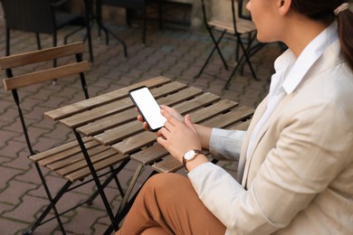 Photo of Woman using smartphone at table in cafe outdoors, closeup