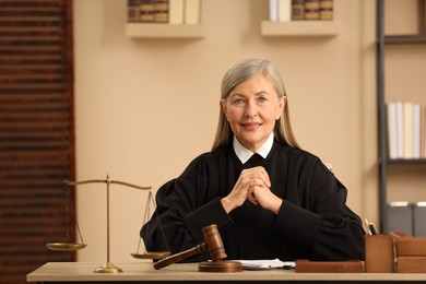 Photo of Judge in court dress working at table indoors. Space for text
