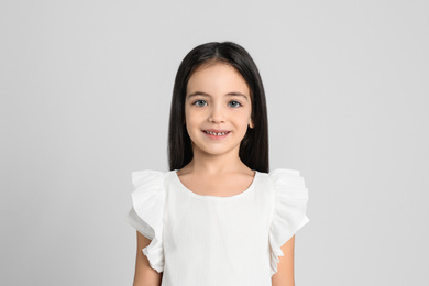 Portrait of cute little girl on light grey background