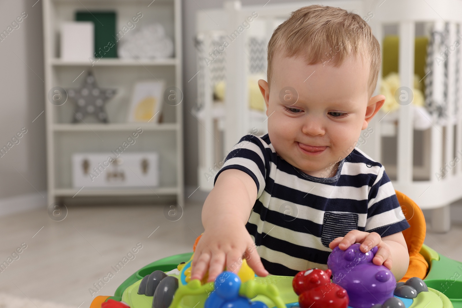 Photo of Portrait of cute baby with toy walker at home, space for text. Learning to walk