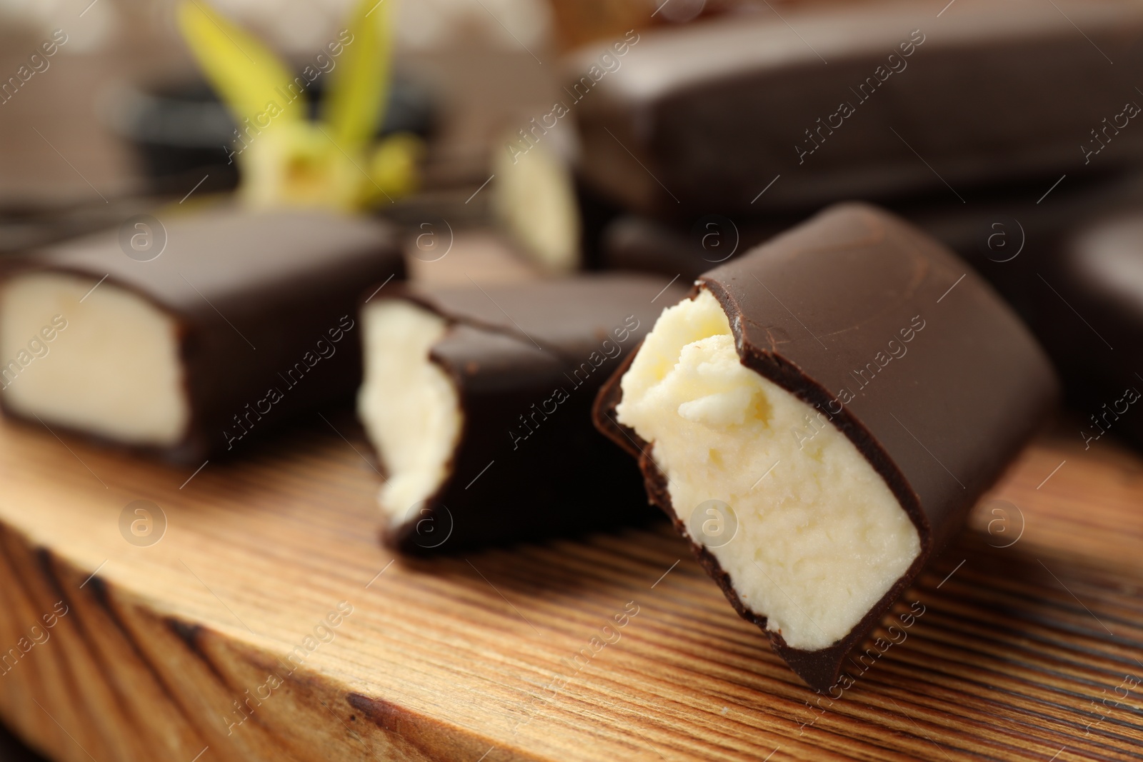 Photo of Glazed curd cheese bars on wooden board, closeup