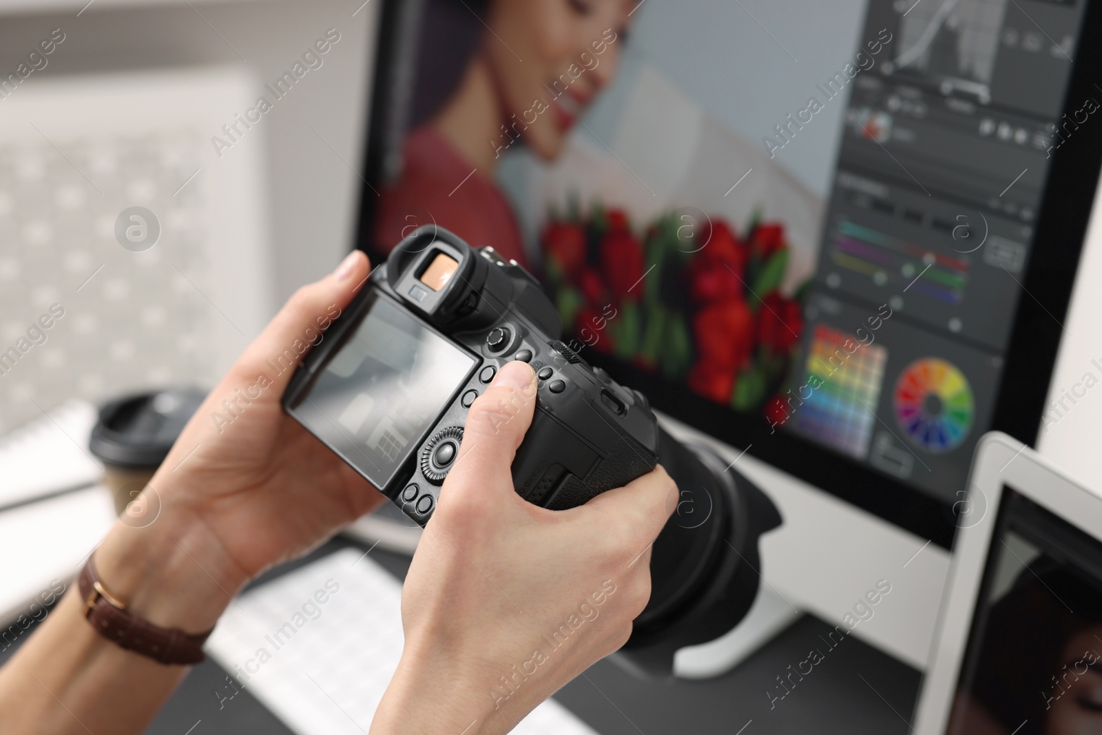 Photo of Professional photographer with digital camera at table indoors, closeup