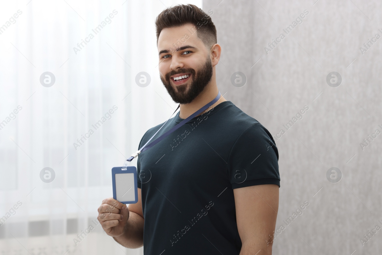 Photo of Happy young man with blank badge indoors