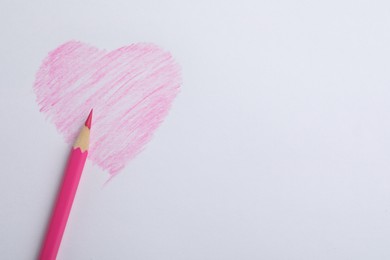 Drawing of heart and pink pencil on white background, top view