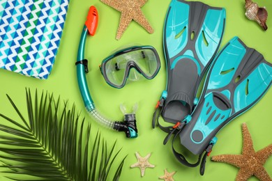 Flat lay composition with diving mask, fins and beach accessories on green background