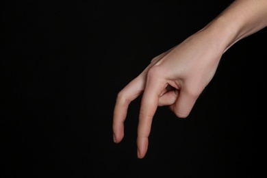 Photo of Woman imitating walk with hand on black background, closeup. Finger gesture