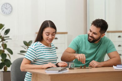 Happy young couple counting money at wooden table indoors