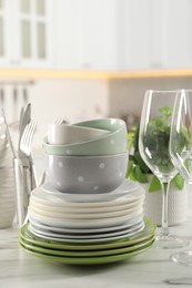 Many different clean dishware, glasses and cutlery on white marble table indoors