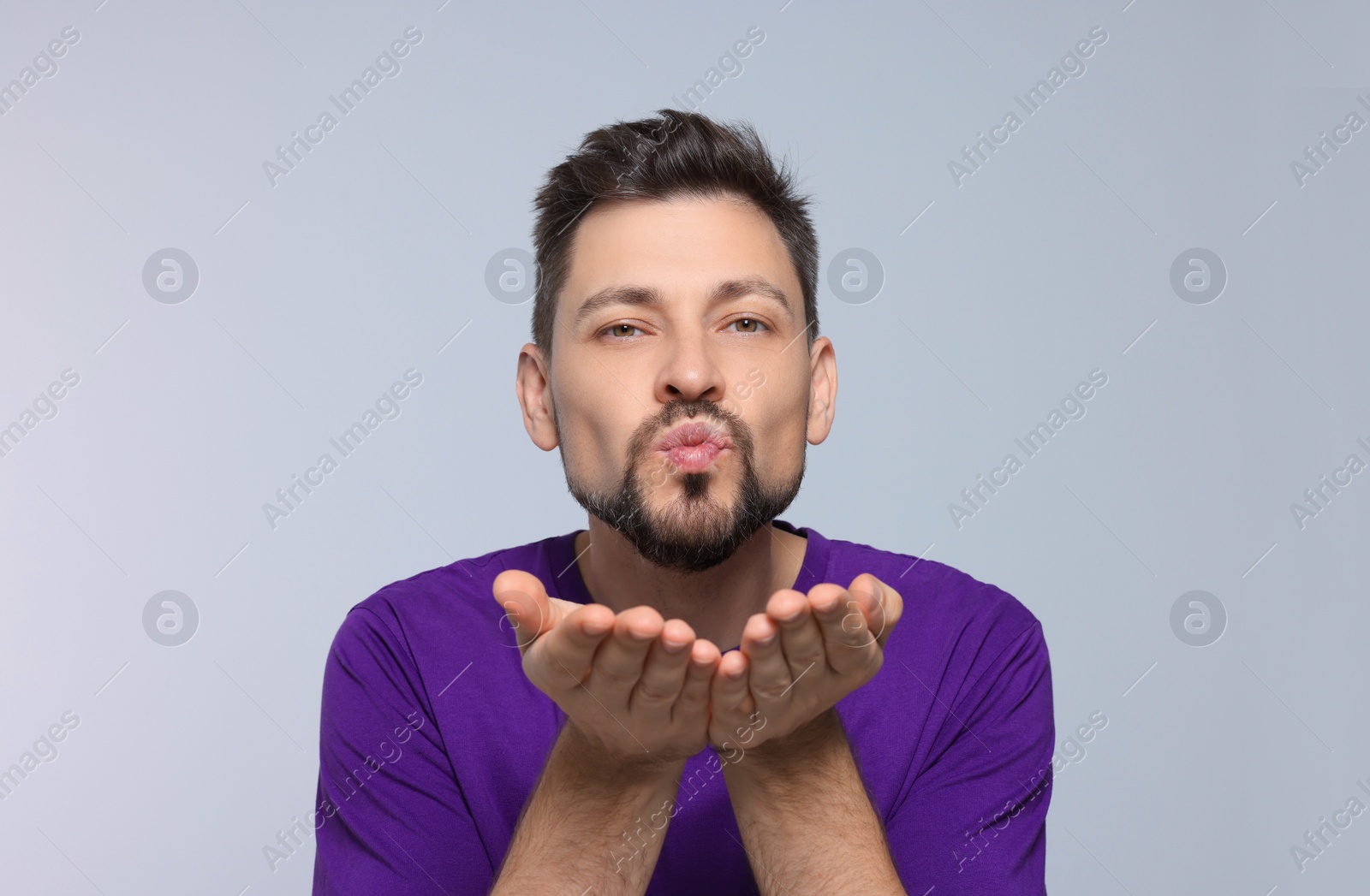 Photo of Handsome man blowing kiss on light grey background