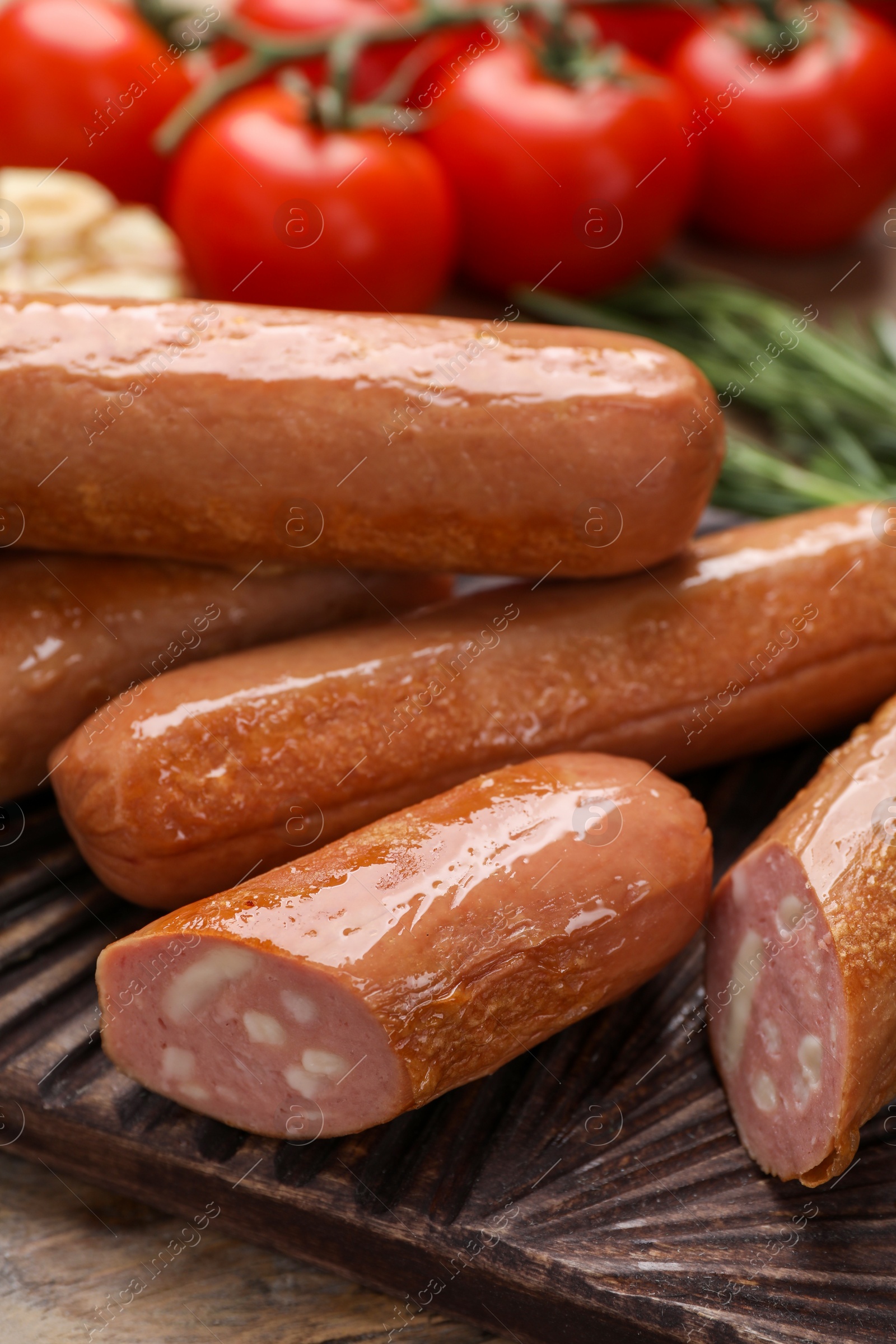 Photo of Delicious vegan sausages and tomatoes on wooden table, closeup