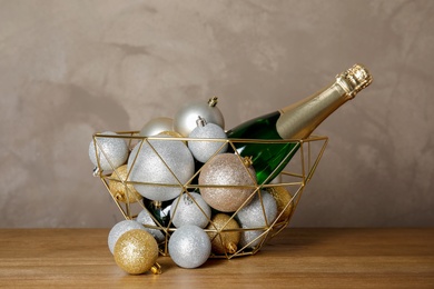 Photo of Christmas balls with bottle of champagne in decorative basket on table