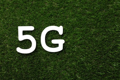 Photo of 5G technology, Internet concept. Number and letter on green grass, flat lay. Space for text