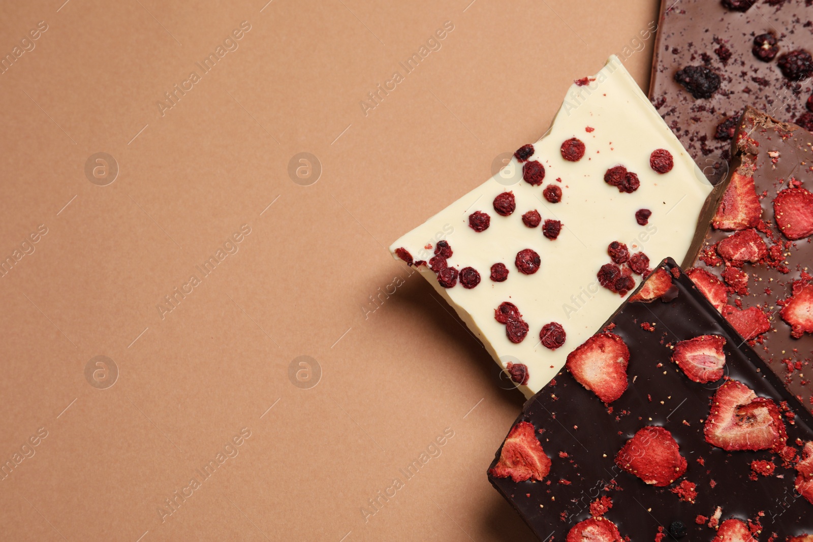 Photo of Different chocolate bars with freeze dried fruits on beige background, flat lay. Space for text