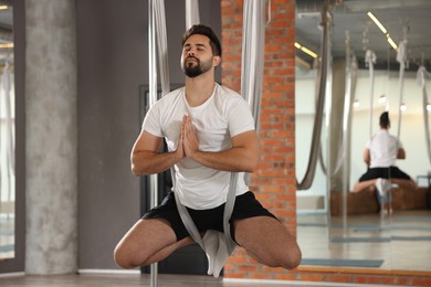 Photo of Young man practicing fly yoga on hammock in studio