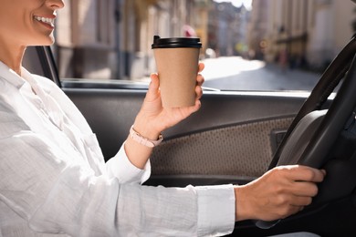 Coffee to go. Woman with paper cup of drink driving her car, closeup