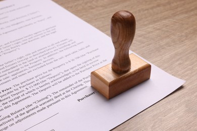 Photo of One stamp tool and document on wooden table, closeup