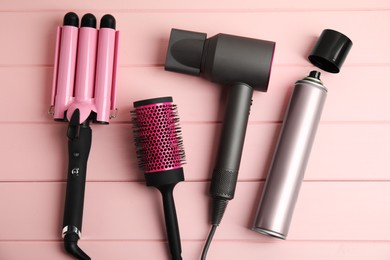 Photo of Flat lay composition with hairdressing equipment on pink wooden background